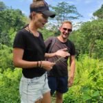Guest holding edible fern shoots along hiking trail in Aik Berik village