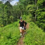 Nature walk through plantation area on hiking route to waterfalls in Aik Berik