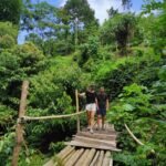Guests crossing small bridge on hiking trail to hidden waterfalls in Aik Berik, Lombok